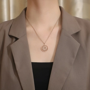 Vue détaillée du collier pendentif Om en or rose avec découpe soleil sur un mannequin