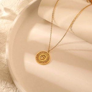 Collier avec pendentif soleil Om hindou en acier titane sur une assiette beige