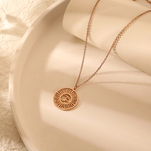 Collier avec pendentif Om hindou or rose et motif soleil sur socle blanc
