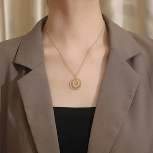 Détail d'un collier pendentif Om doré au motif de soleil porté par un mannequin