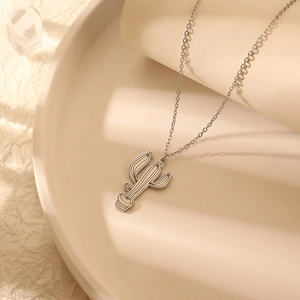 Collier avec pendentif cactus argenté minimaliste sur un plateau pour homme et femme