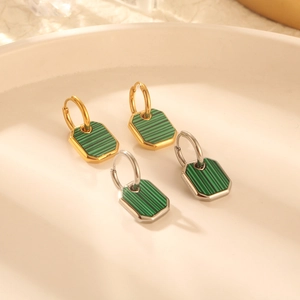Gold and silver octagonal malachite hoop earrings on a minimalist ceramic plate