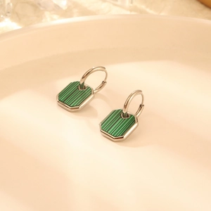 Silver hoop earrings with octagonal green malachite pendants on elegant beige tray