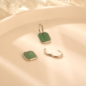 Silver hoop earrings with green malachite octagon pendants on a ceramic jewelry tray
