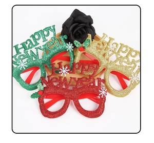 Close-up of glitter Happy New Year glasses in red, gold, and green with festive snowflake motifs