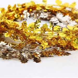 Macro detail of metallic holly leaf tinsel garland in gold and silver for holiday decor