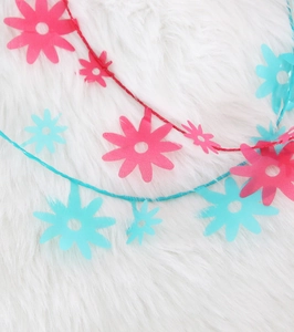 Primo piano della ghirlanda di margherite rosa e blu per decorazioni di feste fai-da-te