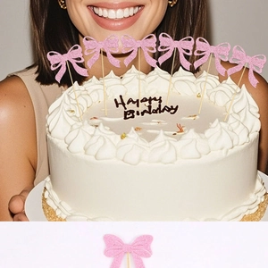 Detailed close-up of pink glitter bow cake toppers held on a birthday cake