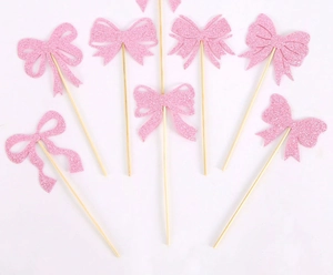 Detailed view of pink glitter bow cupcake toppers with wooden sticks for birthday party
