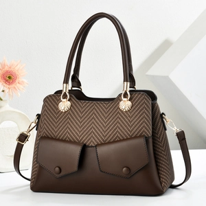 Brown herringbone tote bag with leather trim and gold shell hardware on white background