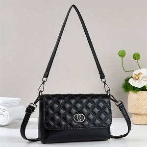 Elegant black quilted crossbody bag with silver hardware and chain strap on marble
