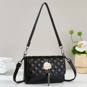 Close-up of black quilted crossbody bag with pink rabbit metal clasp and chain tassel detail