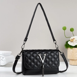 Macro detail of black quilted leather texture with silver V logo and metallic fringe