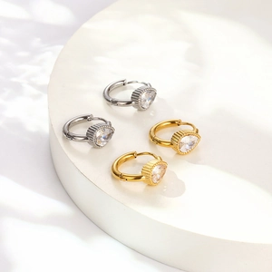 Dettaglio di orecchini con zircone a goccia in oro e argento con metallo lucido