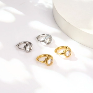 Dettagli di orecchini a cerchio oro e argento con strass rotondi e bordo con texture