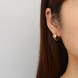 Dettaglio orecchino a cuore dorato con zircone centrale e bordo con micro sfere