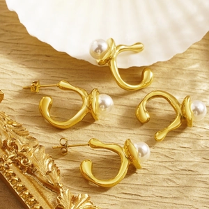Irregular gold lava-style pearl stud earrings and ear cuffs set on a shell backdrop