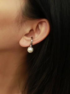 Detailed close-up of a silver stainless steel ear cuff with a white pearl on an ear
