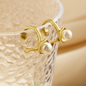Detail of gold clip-on earrings with white pearls on a glass rim in a luxury setting