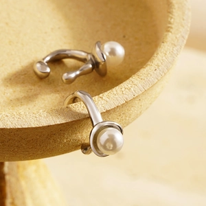 Detailed macro view of irregular silver pearl ear cuffs on a textured stone tray