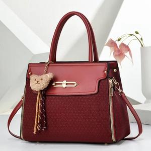 Elegant deep red women's handbag with gold hardware and plush bear charm accent