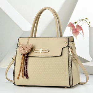 Detail of beige handbag featuring V-pattern weaving texture and brown plush bear charm