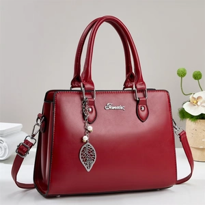 Elegant red PU leather handbag with gold leaf pendant and pearl detail in front view