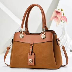 Brown patchwork corduroy handbag with golden hardware on a minimalist white backdrop