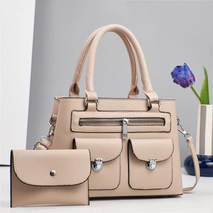 Detail view of beige pebbled leather tote set with multiple pockets and silver hardware