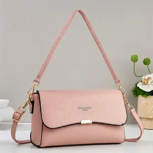 Detailed shot of pink pebble grain leather crossbody bag with silver buckle and branding