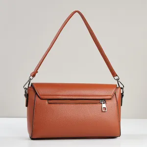 Close-up of caramel brown pebble leather crossbody bag showing back zipper pocket and strap