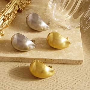 Macro shot of matte brushed teardrop earrings in gold and silver finish with organic shape