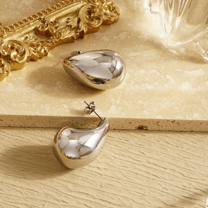 Detailed view of polished silver waterdrop earrings on a textured stone surface