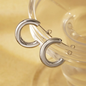 Polished silver C-shaped titanium steel hoop earrings with glossy finish on glass