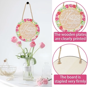 Détail d'une plaque en bois en cœur avec imprimé floral et citation mère-fille au mur