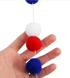 Detail showing soft red white and blue pom poms on string for Independence Day decoration