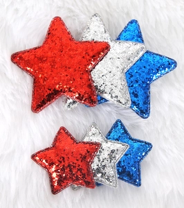 Detail of red silver and blue sequined star hair clips on soft white faux fur background