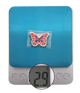 Detail shot showing 2.9g weight of glittery red white blue butterfly patriotic earrings