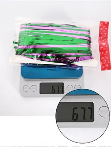 Weight measurement of pink and green tinsel curtain showing 67.7g on digital scale