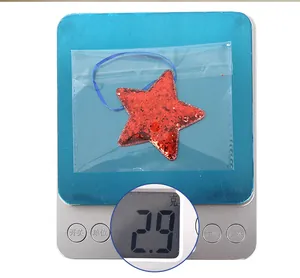 Macro shot of a red sequin star ornament on a digital scale weighing 2.9g for Independence Day
