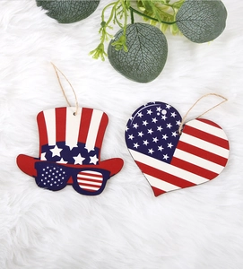 Detail of wooden Fourth of July heart and hat hanging ornaments on a white plush background