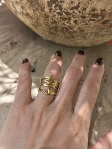 Detailed view of irregular wavy gold ring on finger with organic flowing lines