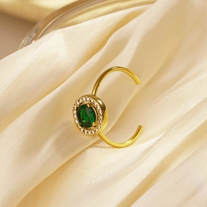 Detailed shot of golden adjustable ring with a round green gemstone on silk fabric