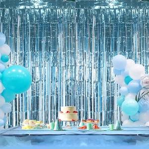 Blue foil fringe curtain backdrop for gender reveal parties with balloons and party props