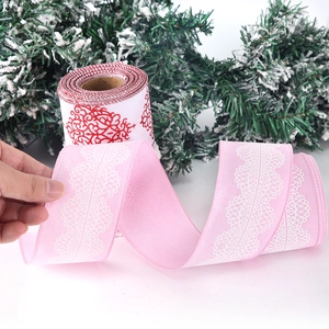 Detail of pink Christmas linen ribbon with white lace print and winter pine background