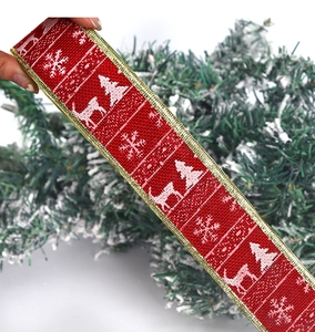Detail of red Christmas ribbon with white reindeer and snowflake prints and gold edges