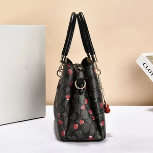 Detail of cherry pattern and C logo print on luxury textured leather handbag with gold hardware