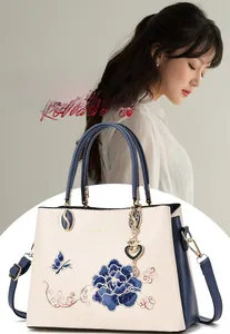 Detail of floral embroidery and heart pendant on a vintage-style contrast handbag