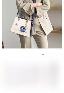 Detail of blue peony embroidery and butterfly on white crocodile texture handbag