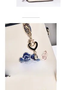 Macro shot of elegant floral embroidery and heart-shaped metal pendant on beige handbag
